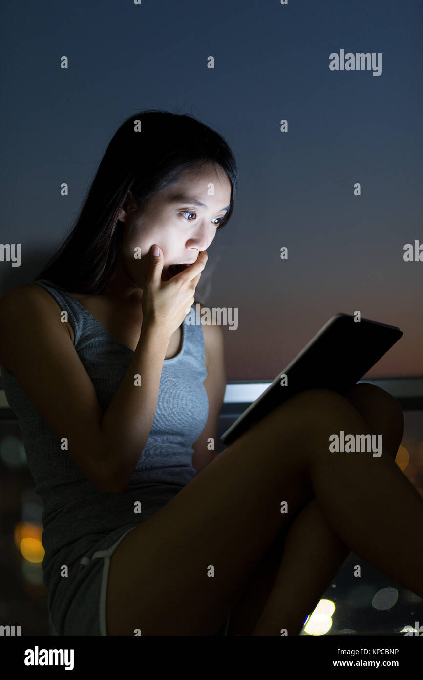 Young Woman feeling shock when watching on tablet pc Stock Photo