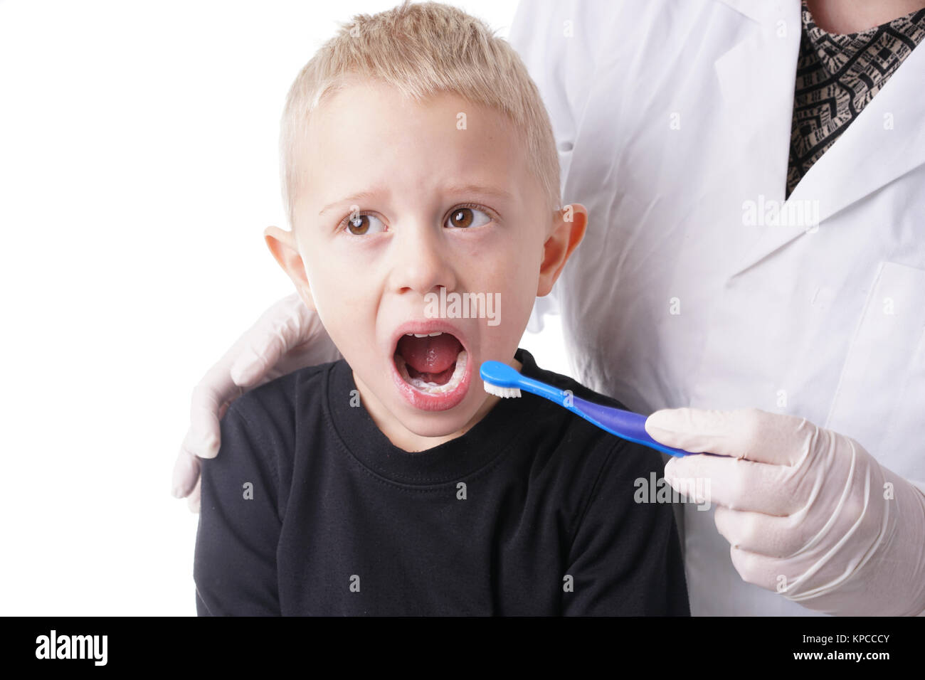 Boy gets help by the Dentist to brush his teeth Stock Photo