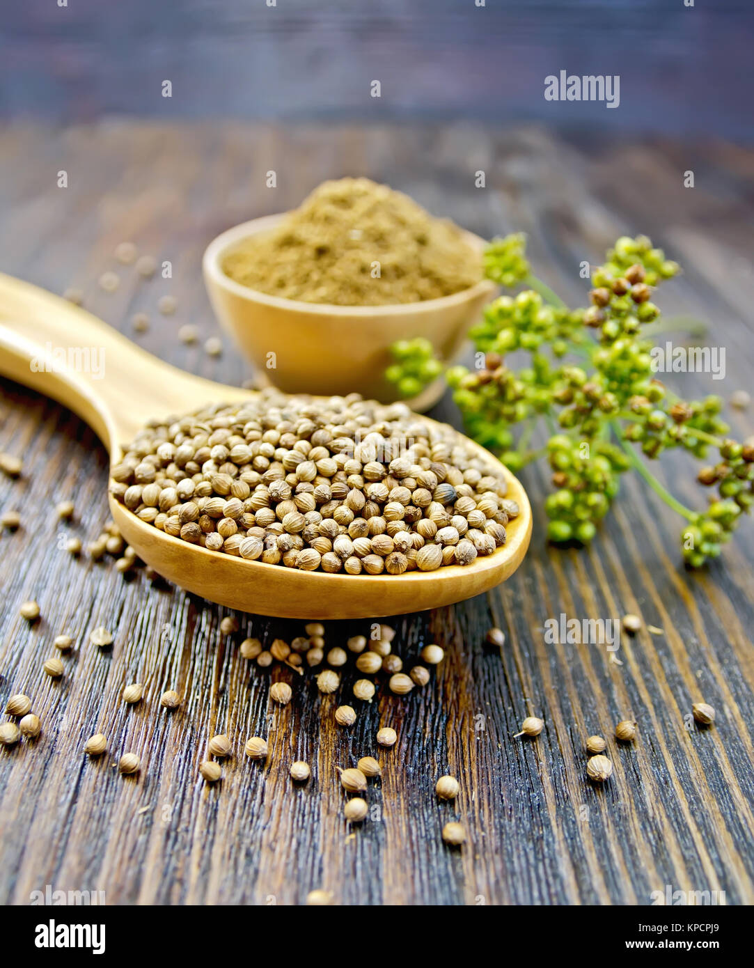 Coriander in bowl and spoon on board Stock Photo