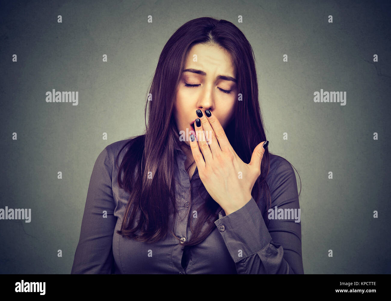 Young covering mouth while yawning sleepy on gray backdrop