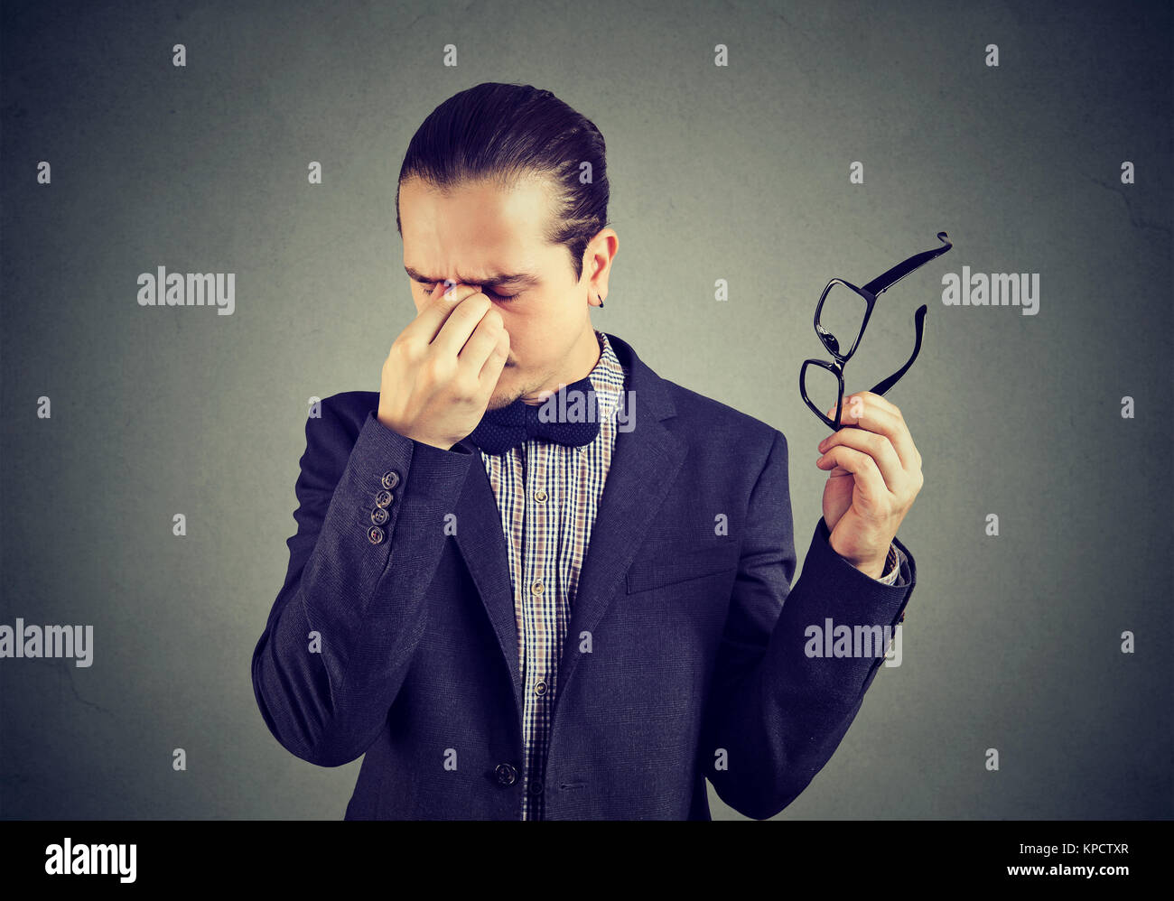 Elegant man taking off glasses and rubbing nose bridge looking tired