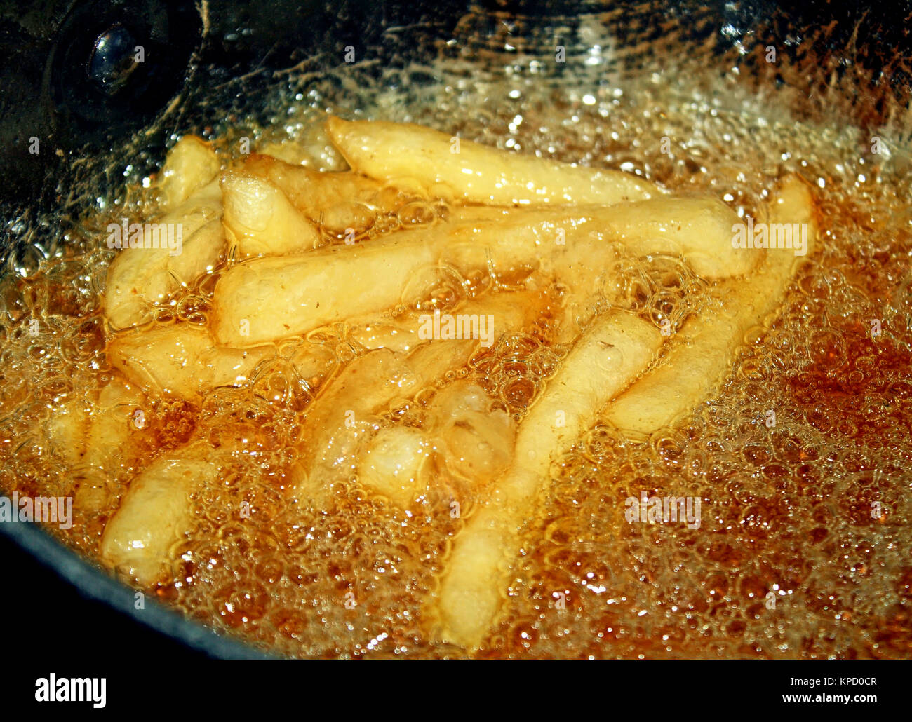 French fries cooking in oil filled deep fryer Stock Photo