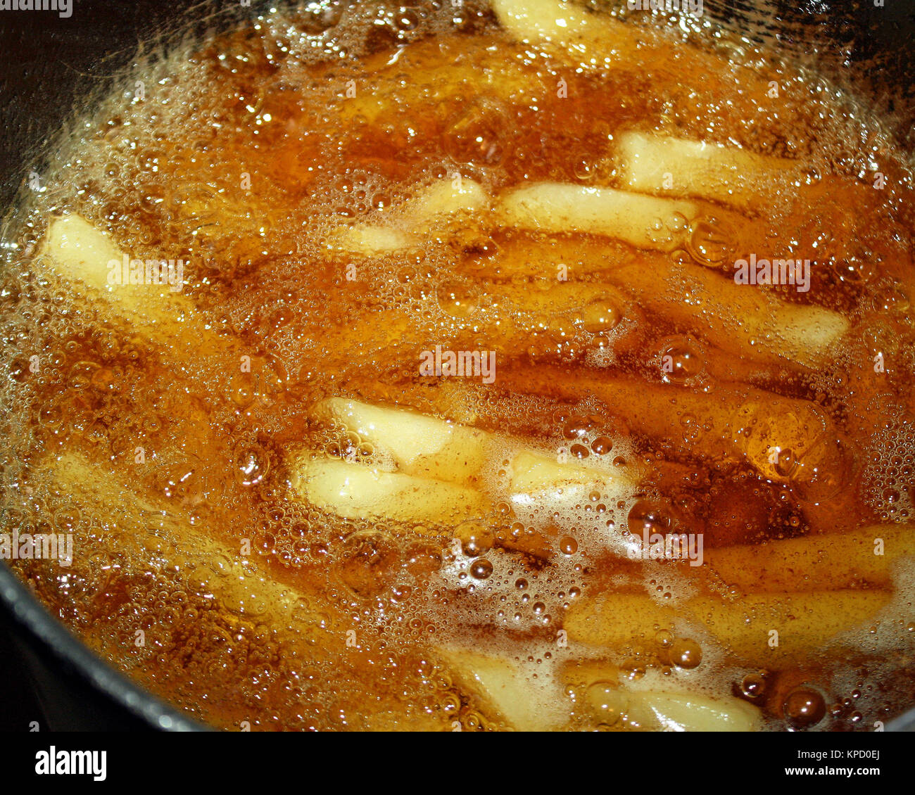 French fries cooking in oil filled deep fryer Stock Photo