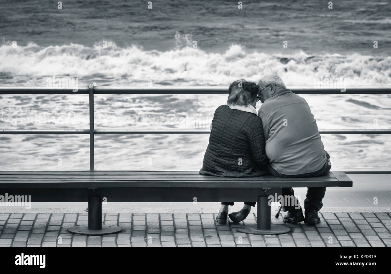 Rear view of elderly couple looking out to sea. Stock Photo
