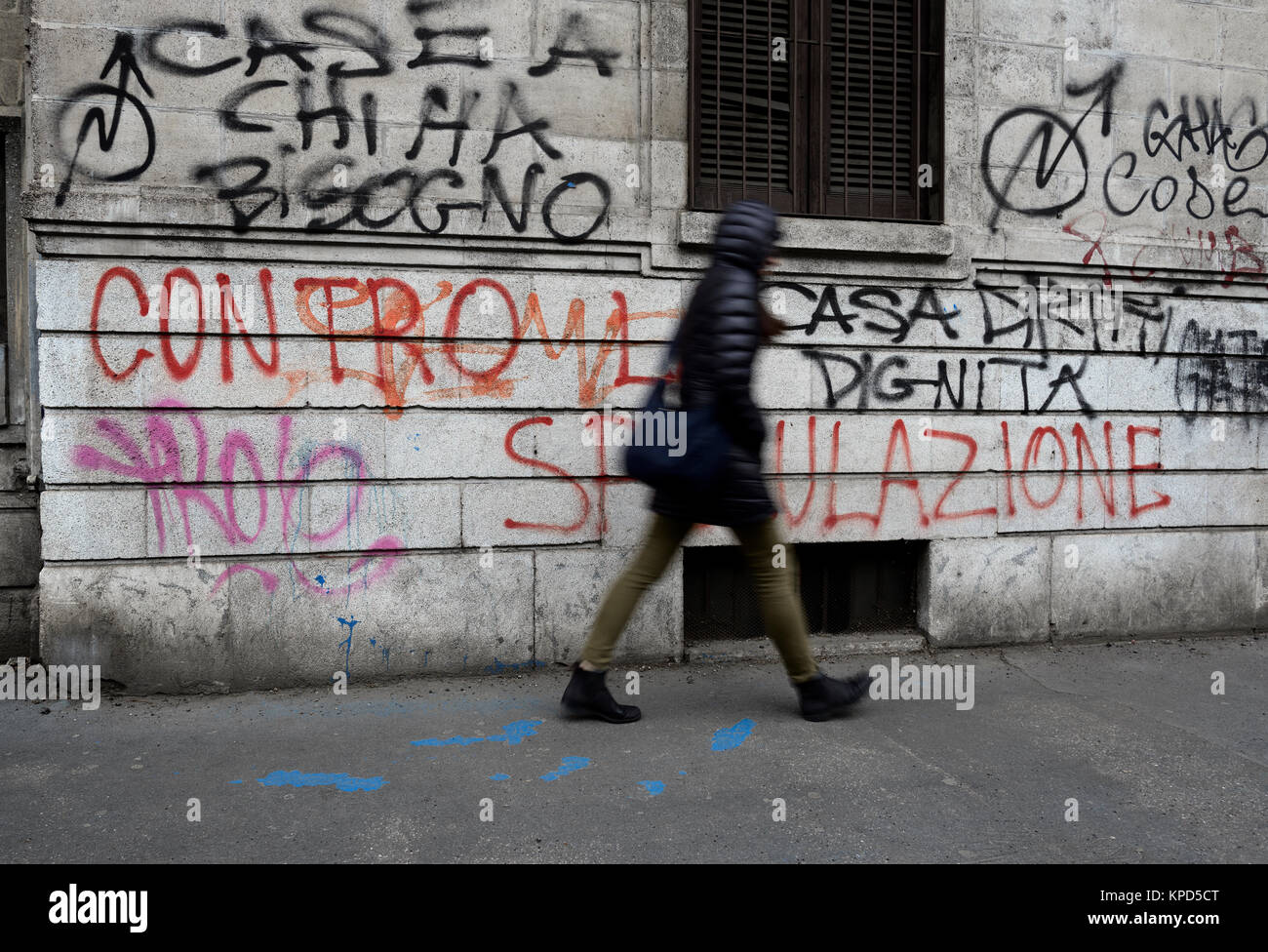 Woman walks near a wall with political writings Stock Photo