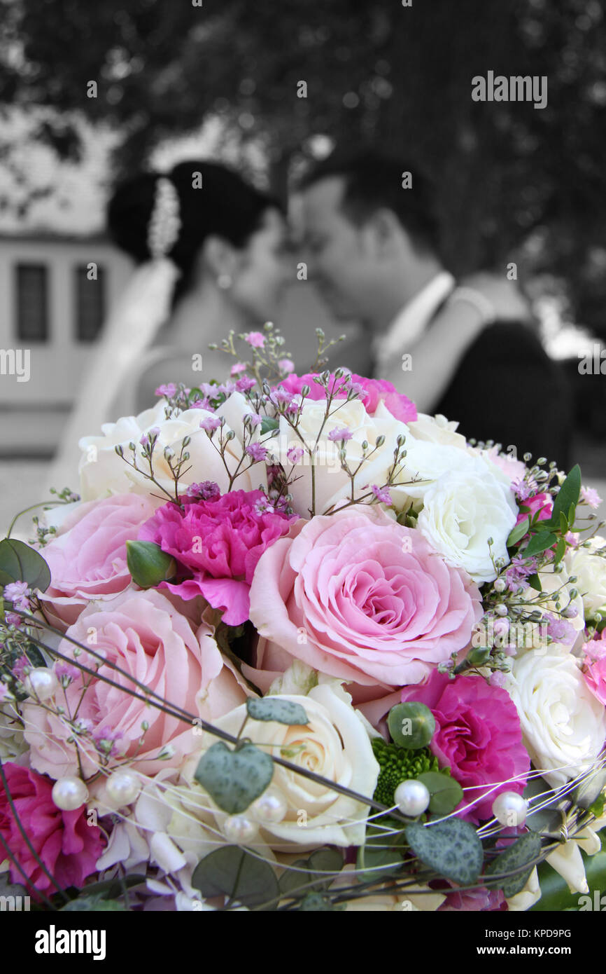 newlyweds turtelt behind bridal bouquet black and white with color Stock Photo