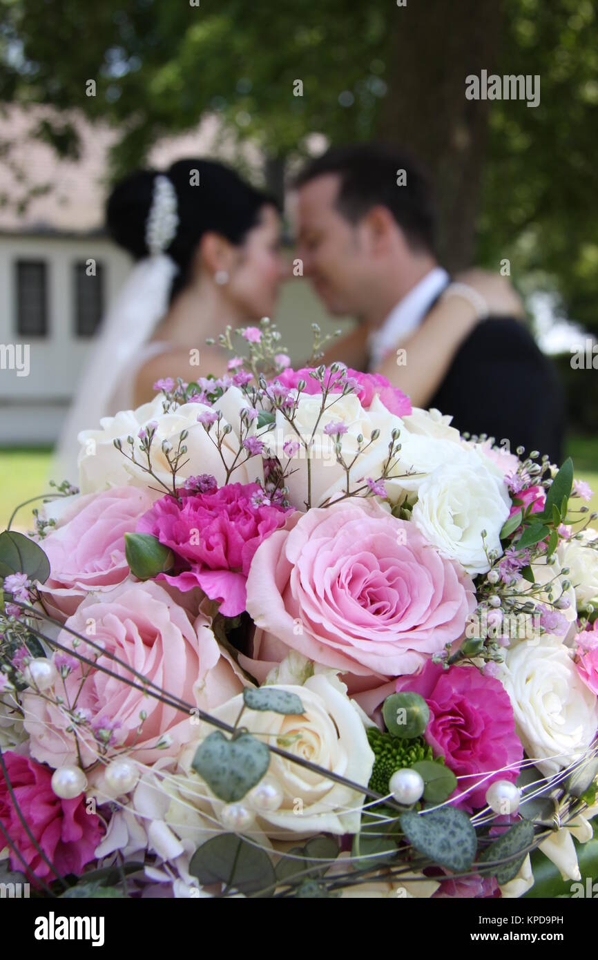 newlyweds turtelt behind bridal bouquet Stock Photo