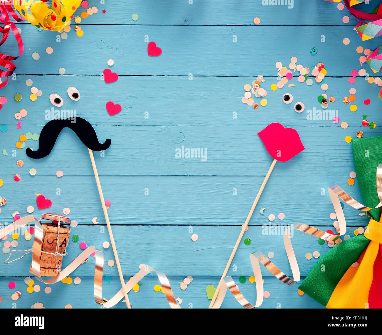Fun photo booth accessories festive background with a loving couple formed  from a mustache and set of luscious red female lips on rustic blue wooden  boards with a frame of party streamers