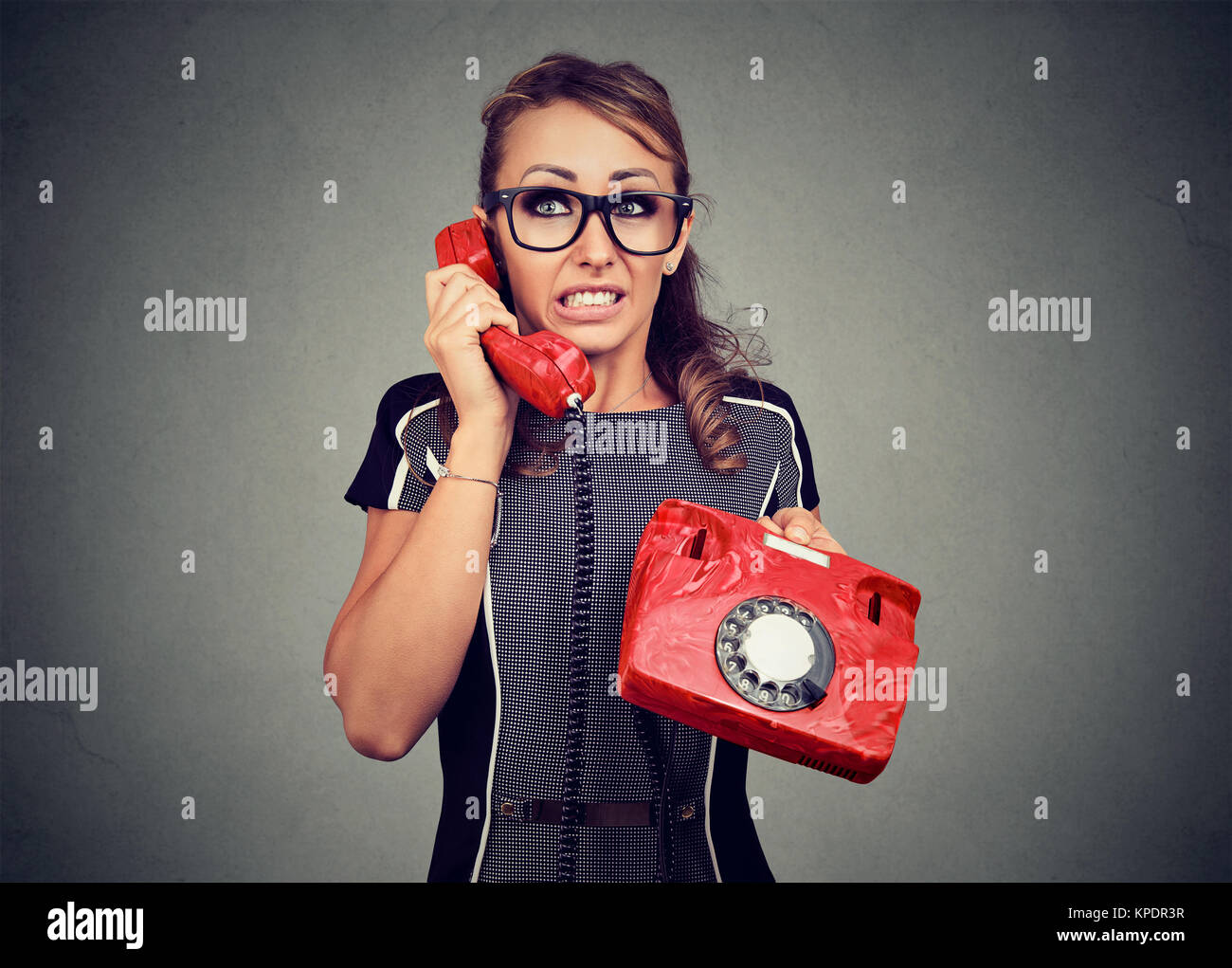 Young nervous woman speaking on retro telephone and looking away having troubles with person on other end. Stock Photo