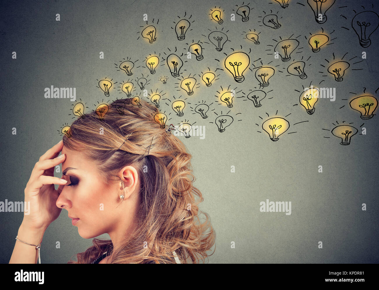 Young woman thinking with concentrated having many ideas with backdrop of burning lightbulbs. Stock Photo