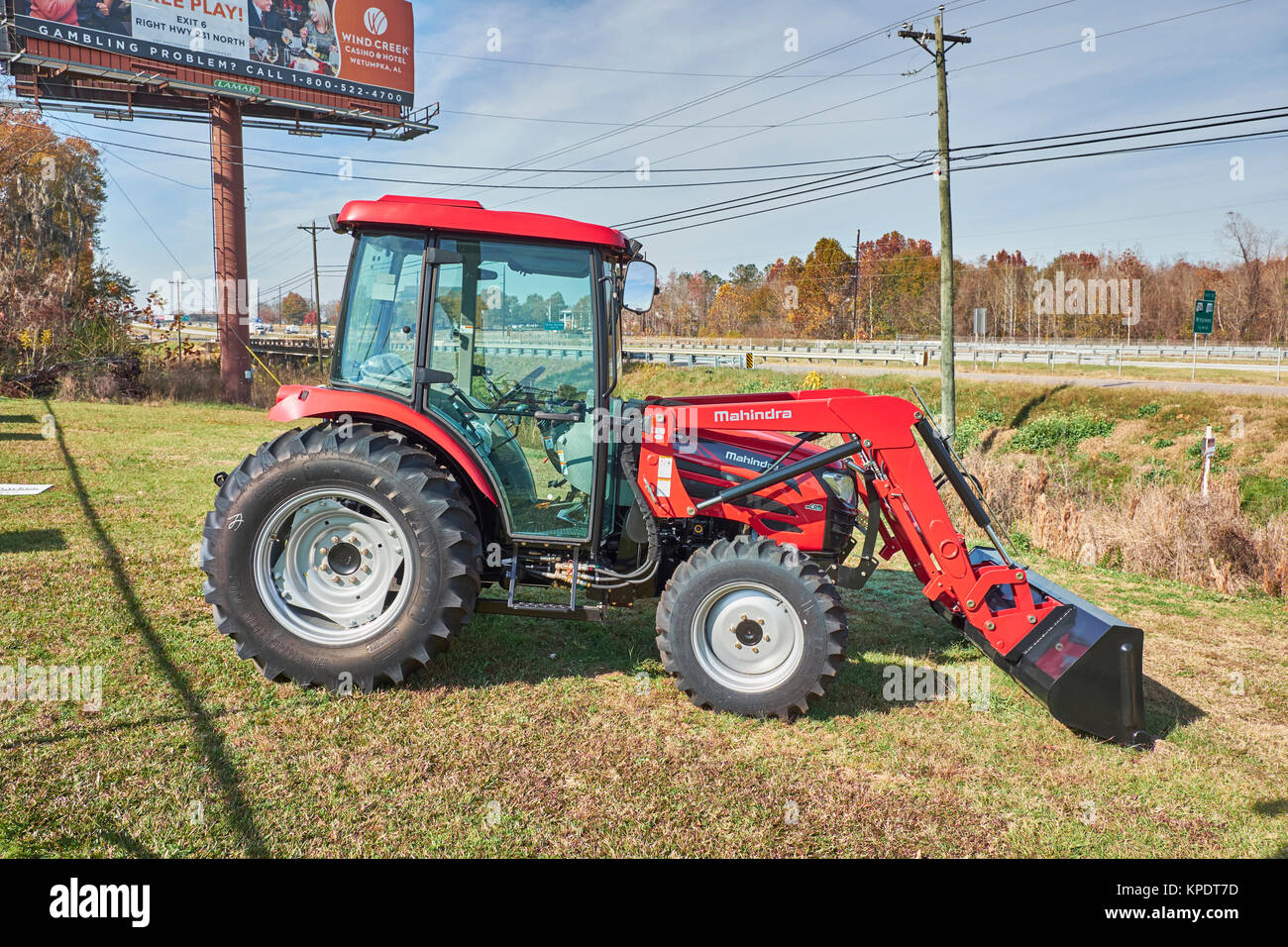 Brand new Mahindra 2565 CL shuttle cab red tractor sitting in front of the dealership with optional front loader. Stock Photo