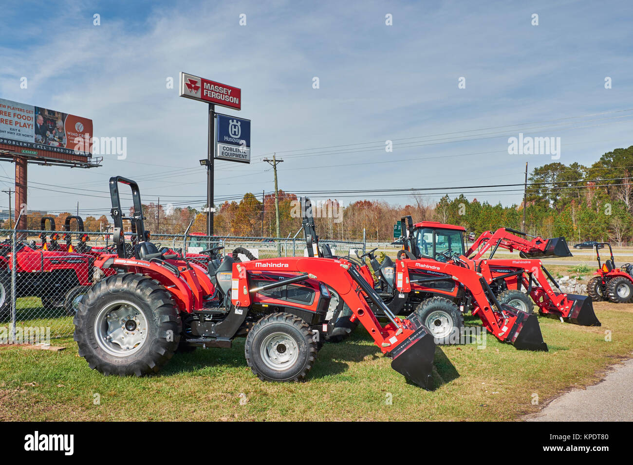 Rows of new Mahindra red tractors and farm equipment for sale at a Mahindra tractor dealership, some with optional equipment. Stock Photo
