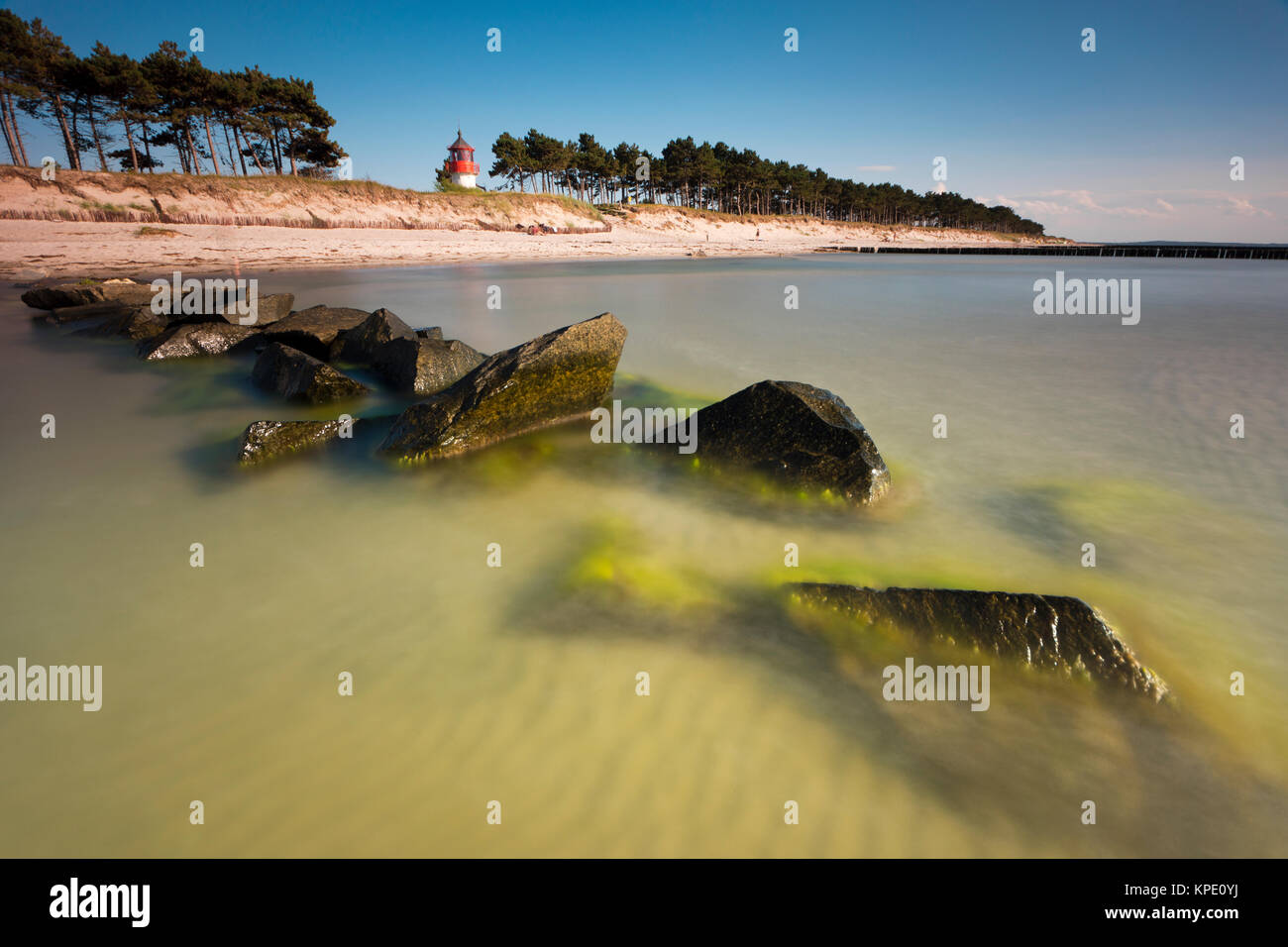 baltic sea with drawing clouds in the sunset with evening red and moody evening light. beach with groins and waves as well as beautiful clouds. Stock Photo