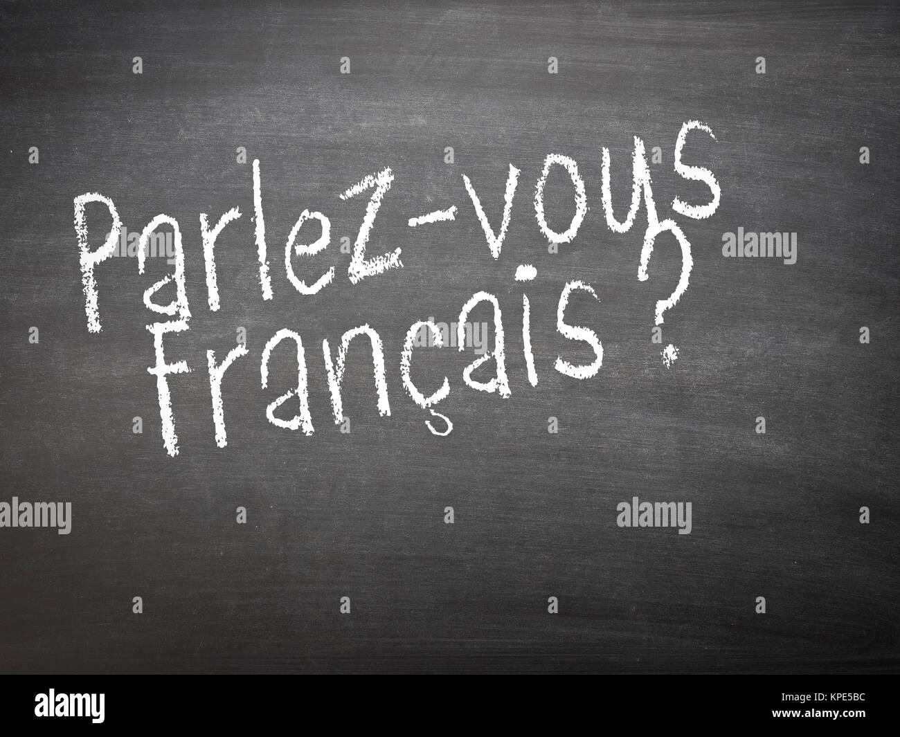 Learning language - French. Learning French language concept of teacher or student writing parlez-vous francais (do you speak French) on blackboard / chalkboard. Stock Photo