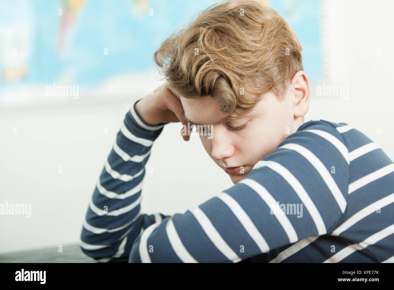 Bored Boy with Head Leaning on Hand in Class Stock Photo
