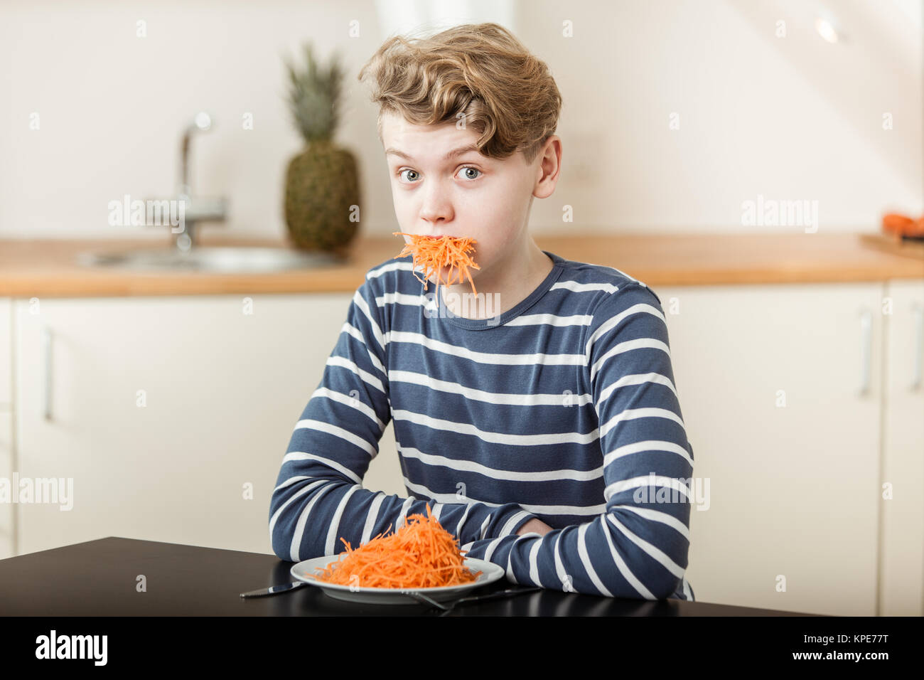 Boy at Table with Mouthful of Shredded Carrots Stock Photo - Alamy