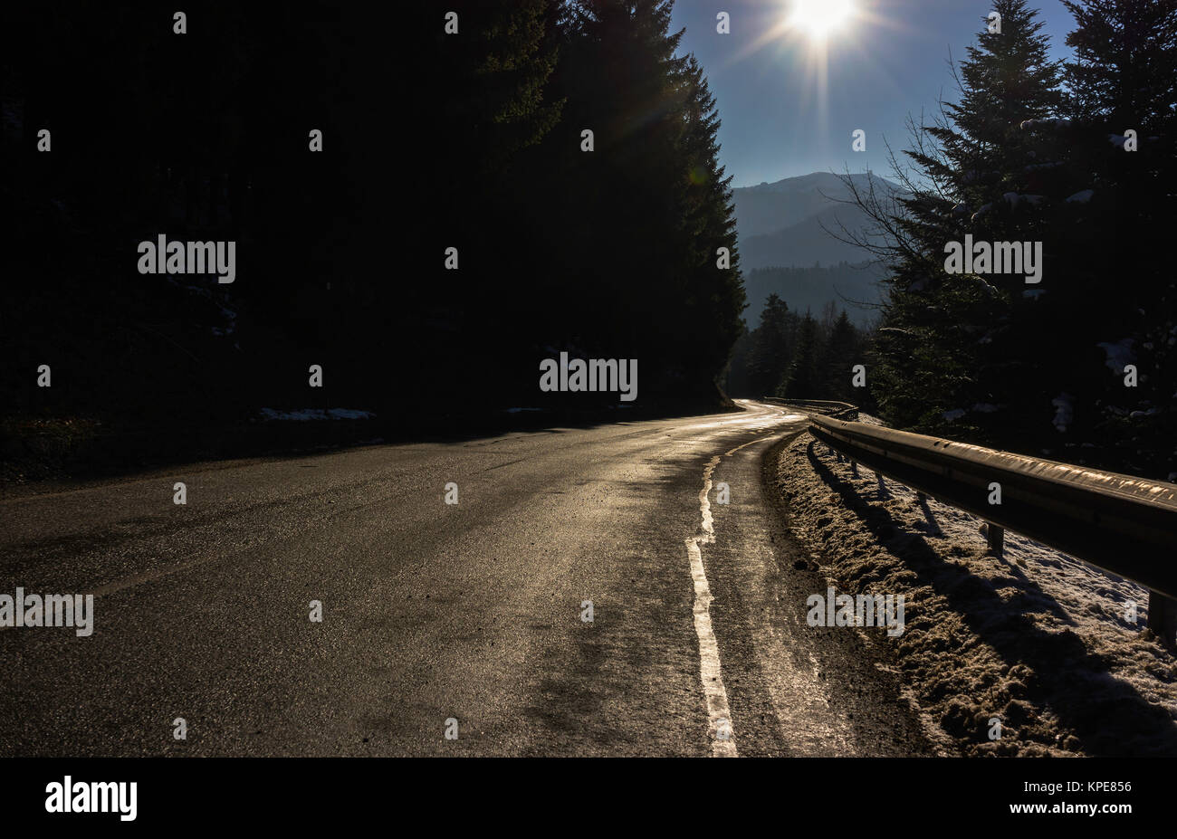 A shiny road curve in the Vosges mountains in winter with sunshine, France. Stock Photo
