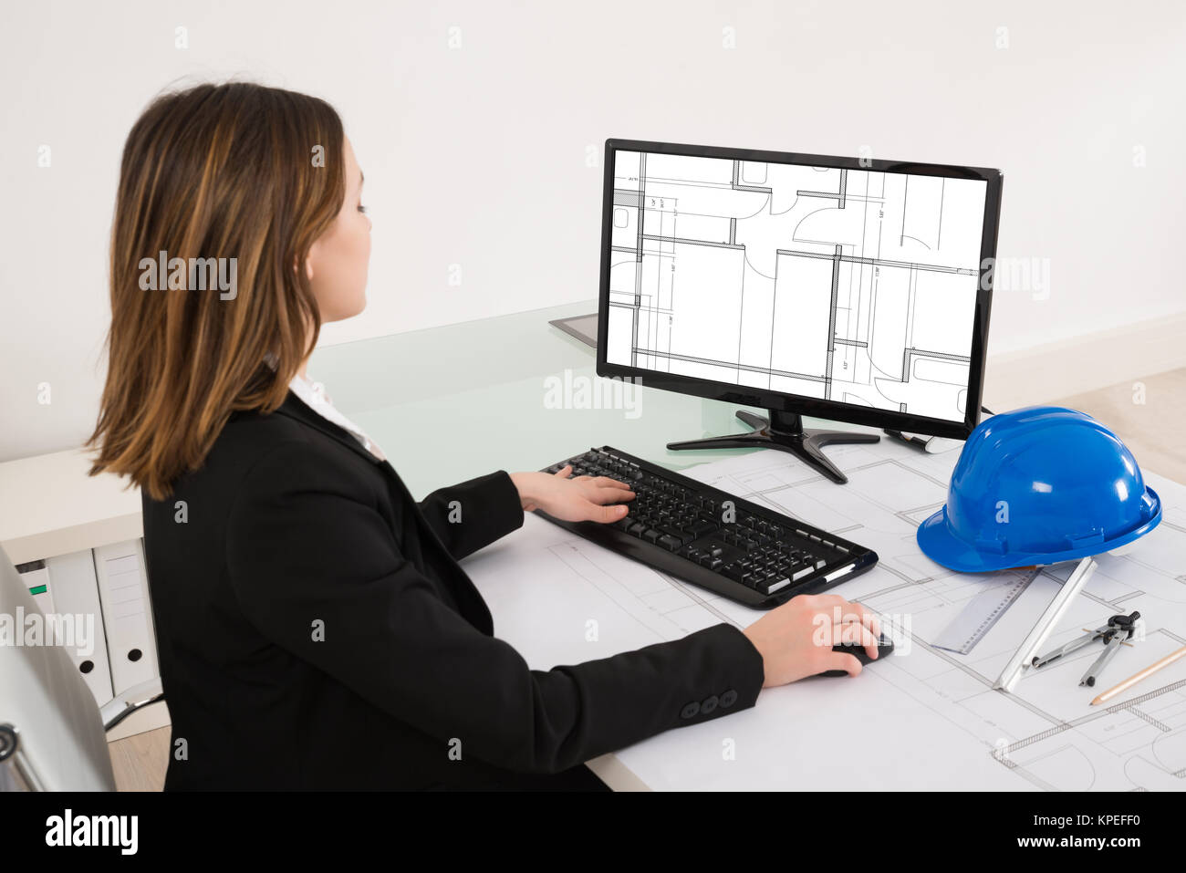 Female Architect Looking At Blueprint On Computer Stock Photo - Alamy