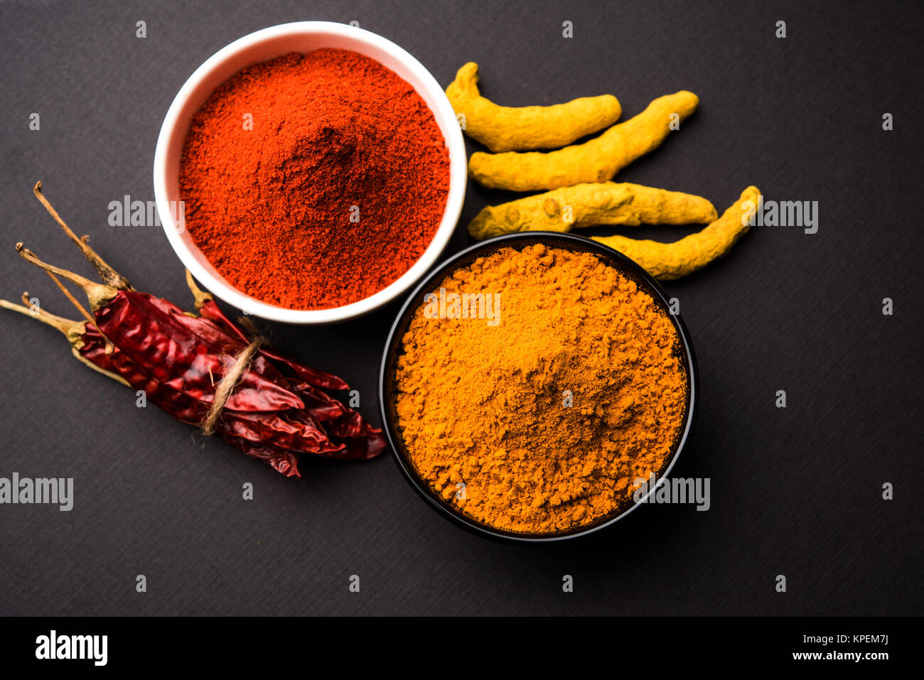 heap of turmeric and red chilli powder in a ceramic bowl on a white or