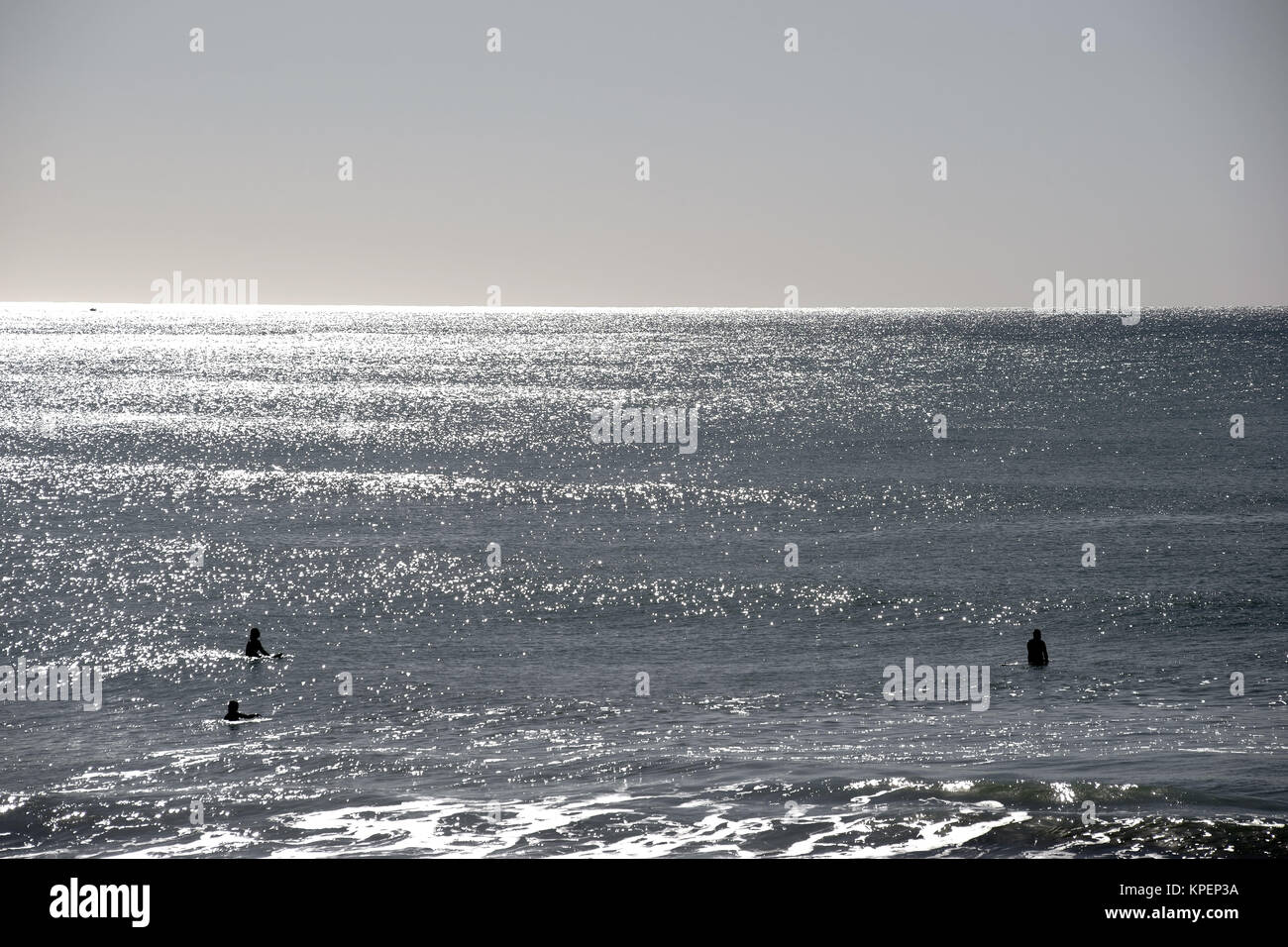 Die Silhouetten von Surfern auf dem Wasser im Gegenlicht am Strand von Oceanside, die auf Wellen warten. Stock Photo