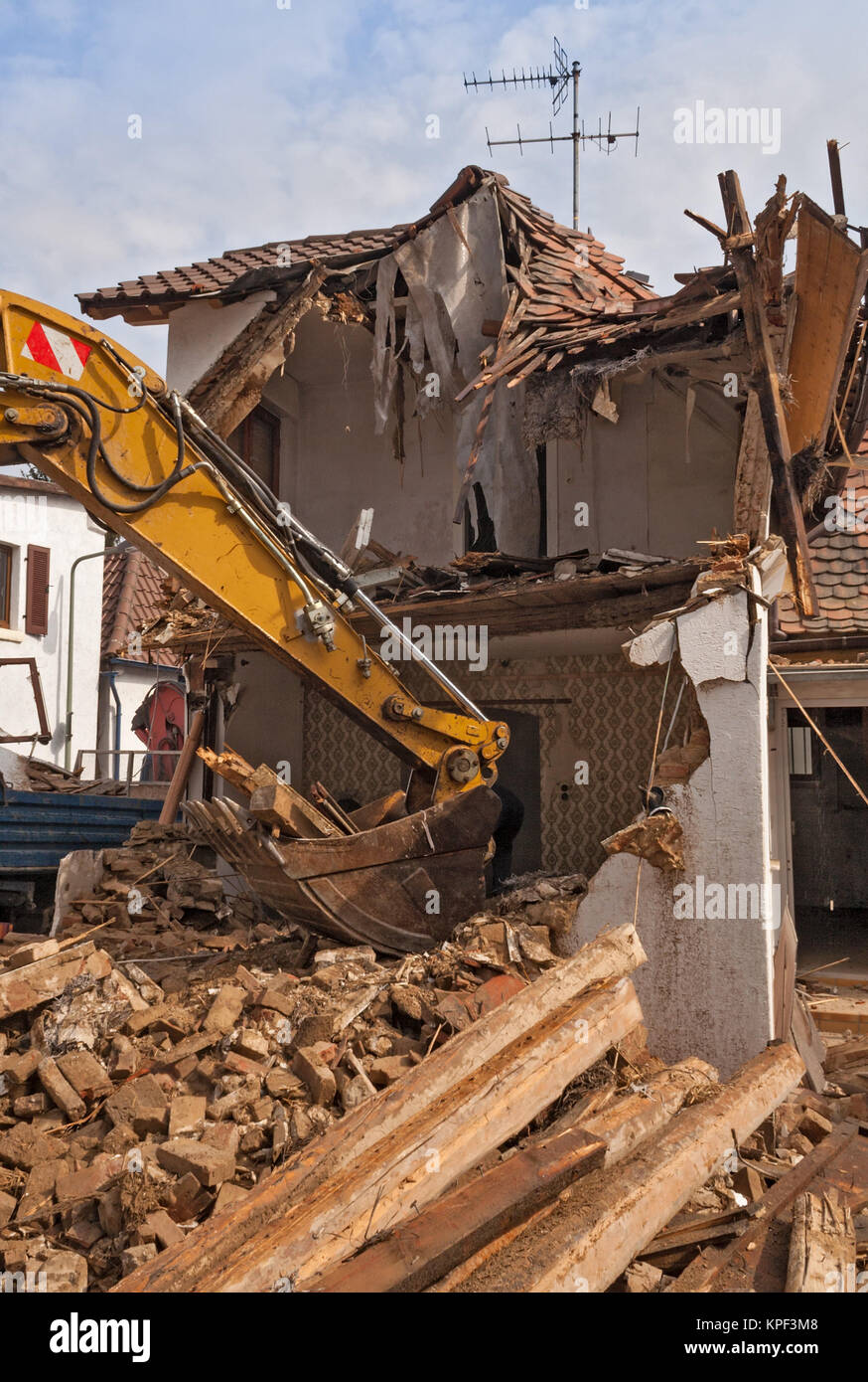 A large track hoe excavator tearing down an old house Stock Photo