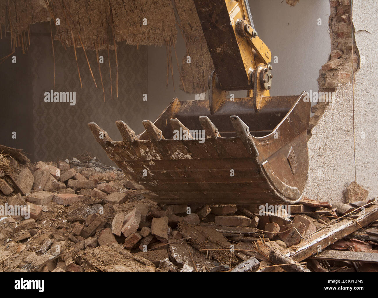 A large track hoe excavator tearing down an old house Stock Photo
