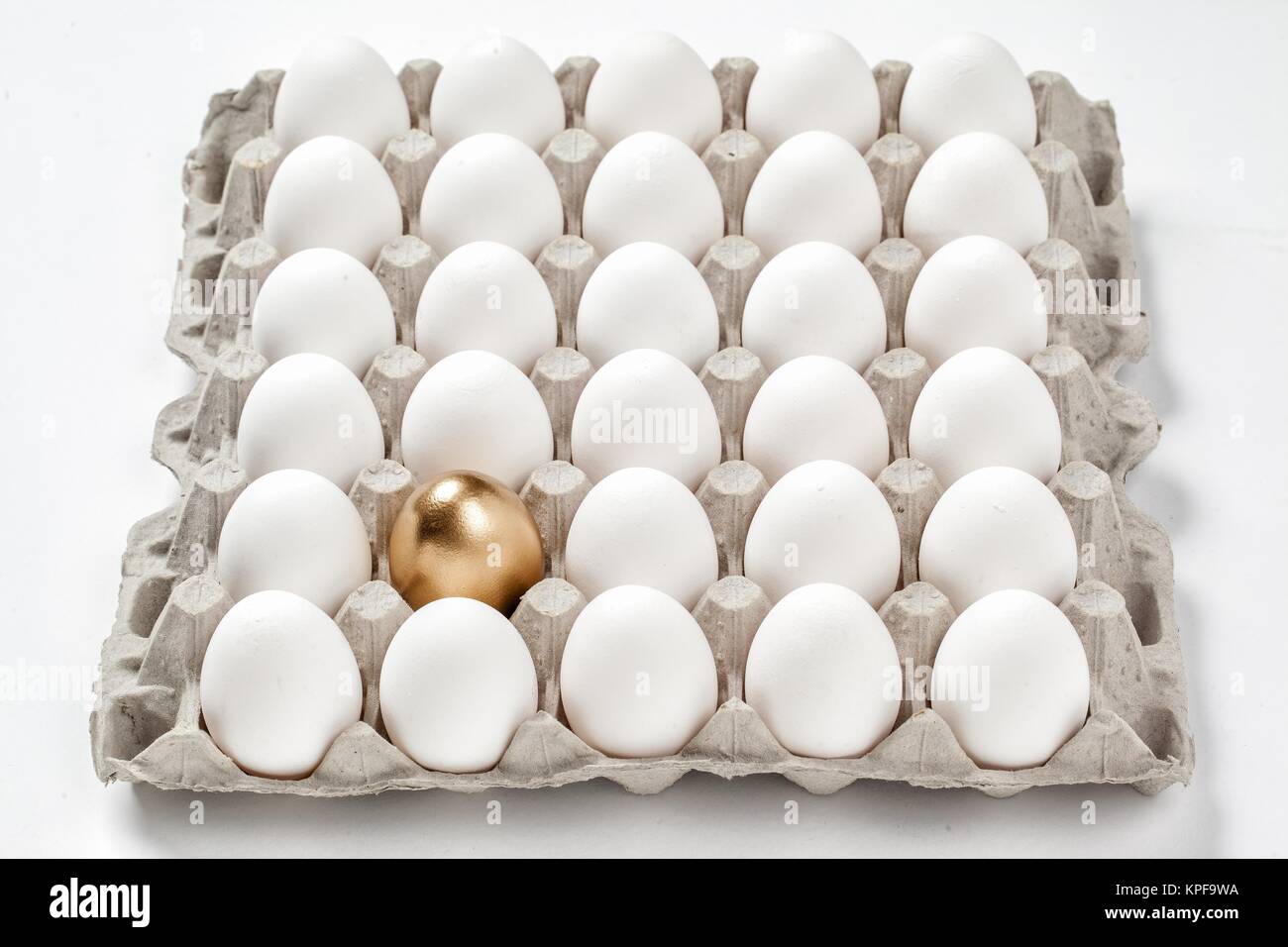 golden egg concept among white eggs in carton pack Stock Photo