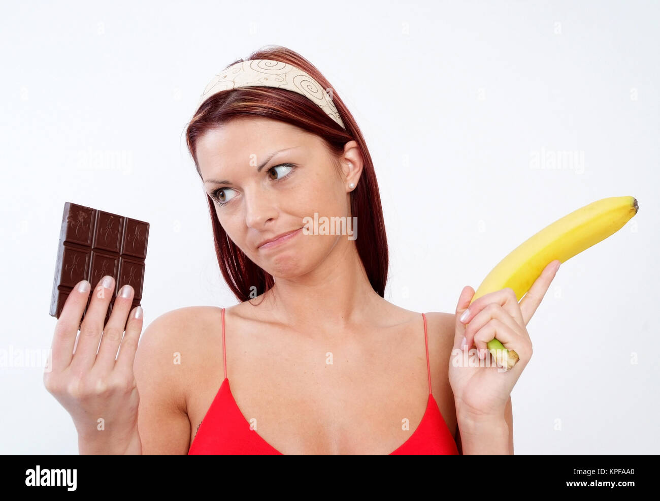 Junge Frau kann sich nicht zwischen Schokolade und Banane entscheiden - woman with chocolate and banana Stock Photo