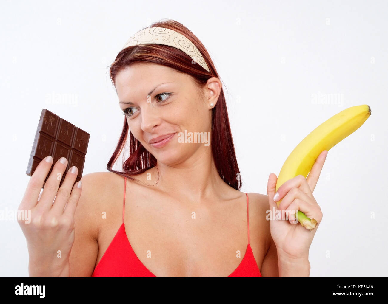 Junge Frau kann sich nicht zwischen Schokolade und Banane entscheiden - woman with chocolate and banana Stock Photo