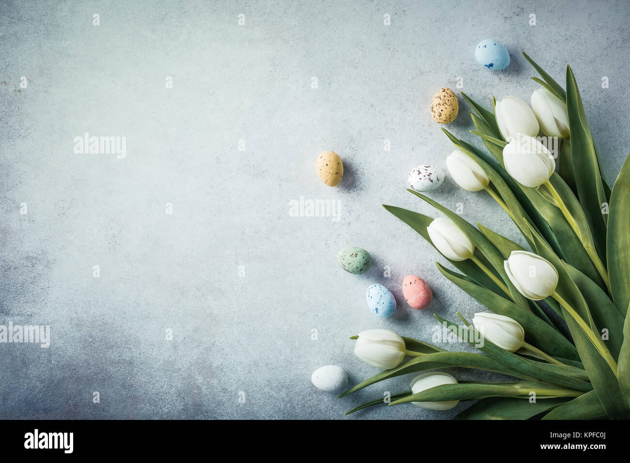 Spring and Easter background. White tulips with colorful quail eggs ...