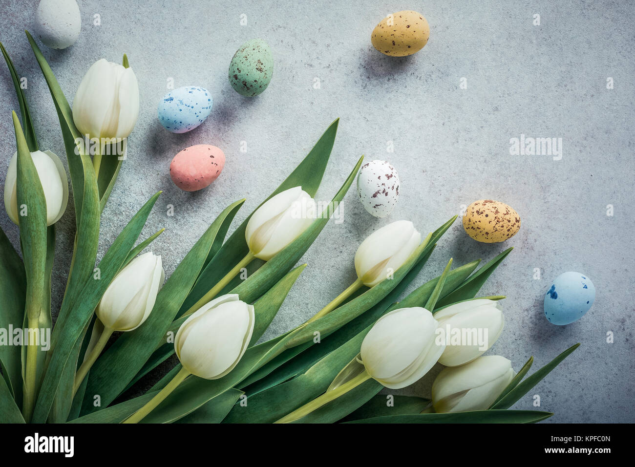 Spring and Easter background. White tulips with colorful quail eggs ...