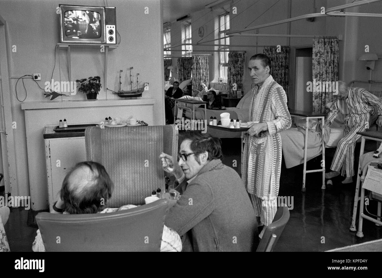 The 1970s National Health Service (NHS) lunch time at Charing Cross Hospital. Patients are allowed to wander around within the ward, eat their meals and watch television. Fulham, London, England circa 1972. UK HOMER SYKES Stock Photo