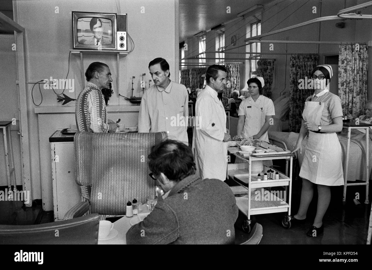 NHS 1970s Uk, doctors Ward Round at Charing Cross Hospital London. Patients allowed to wander around within the ward, eat their meals and watch television.The meal trolley is taken around  the patients by one of the junior nurses. British National Health Service 1972. HOMER SYKES Stock Photo