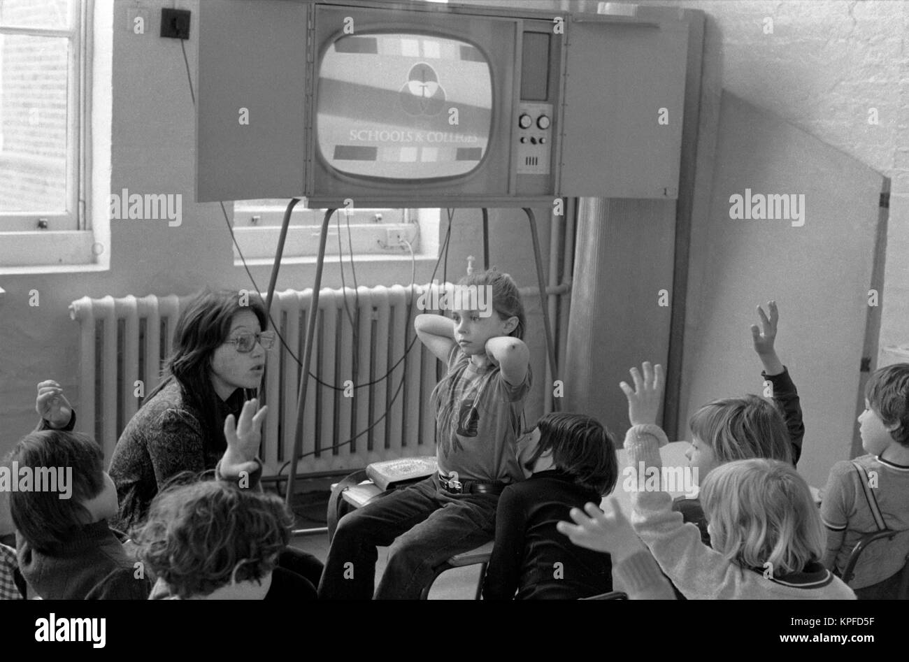 Primary school children 1970s England watching television in classroom with their teacher. 70s UK HOMER SYKES Stock Photo