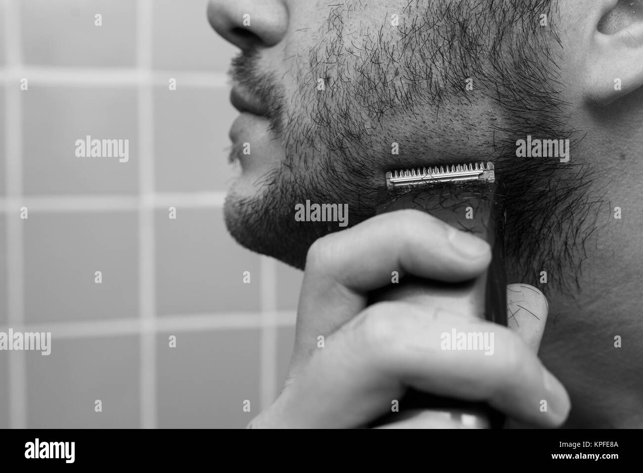 Portrait of young man shaving with trimmer Stock Photo Alamy