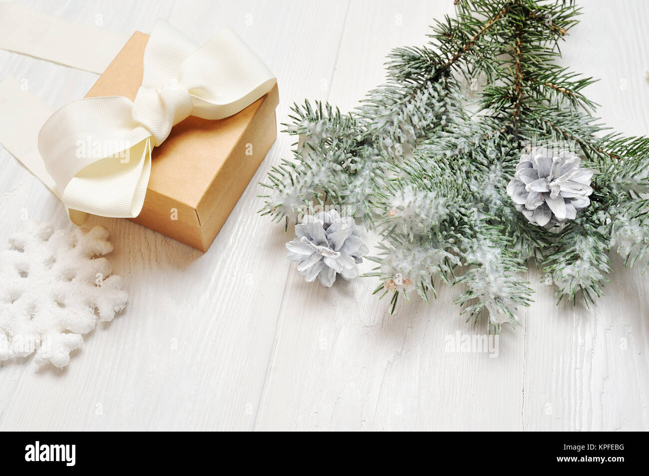 Mockup Christmas gift vintage with snow-covered branch of fir-tree on white wood background Stock Photo