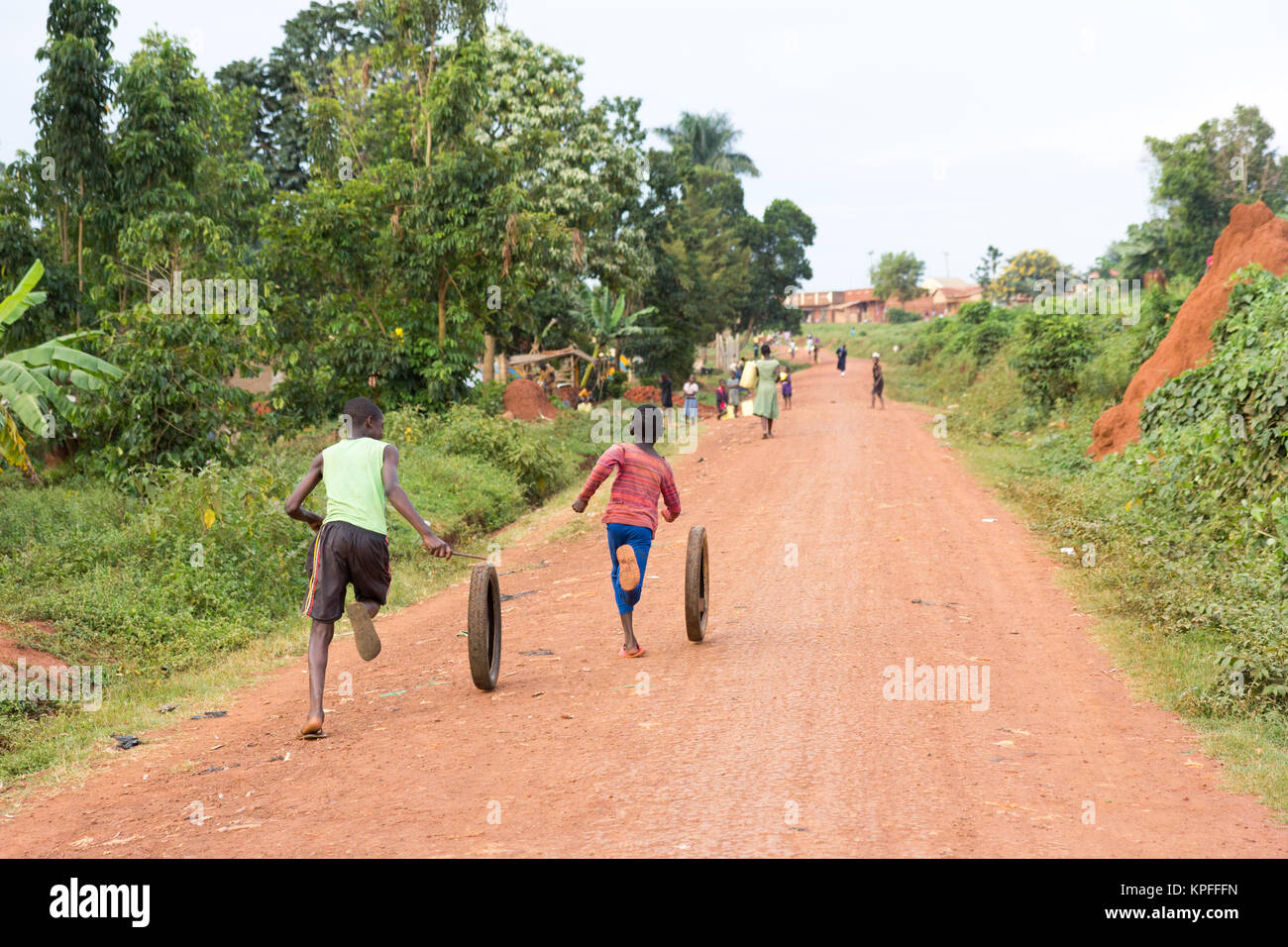 Lugazi, Uganda. June 15 2017. Ugandan children running and spinning a wheel tire. Stock Photo