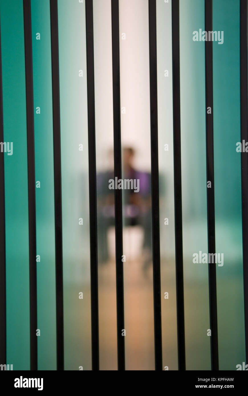 looking through several sheets of glass towards a blurred sitting person Stock Photo