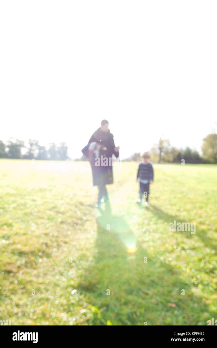 a blurred shot of mother and four year old son walking across british field in the sun Stock Photo
