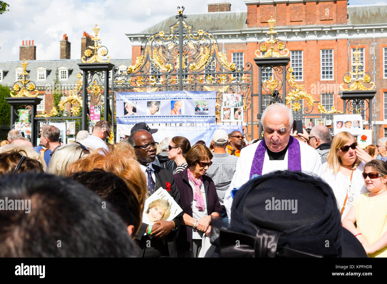 London, UK. A crowd gathers around retired pastor Father Frank Gelli as he says a prayer at the south gate of Kensington Palace on the 20th anniversar Stock Photo