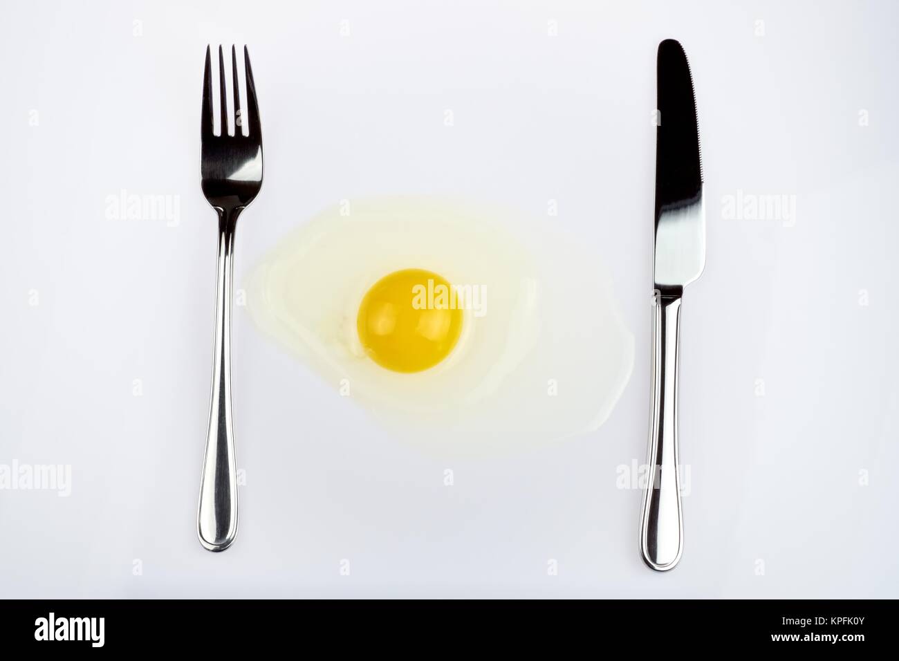 a cracked raw egg with cutlery Stock Photo