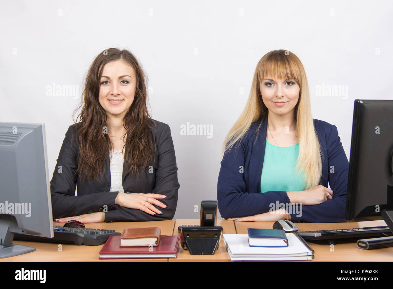 Two young girls sitting at a colleague office table is divided into two jobs Stock Photo