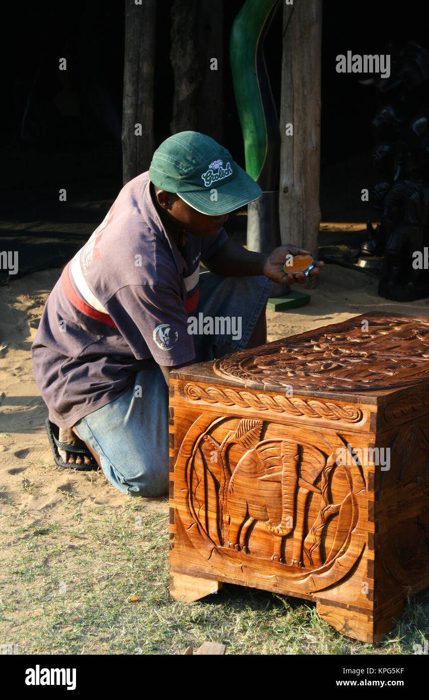 Mozambique, flea market, african man polishing a carved wooden kist in Ponta Do Ouro Stock Photo