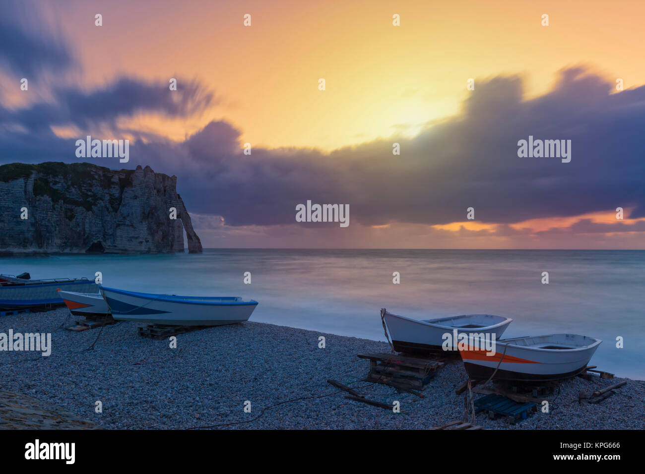Boats on the beach of Etretat at sunset, Porte dAval natural arch in ...