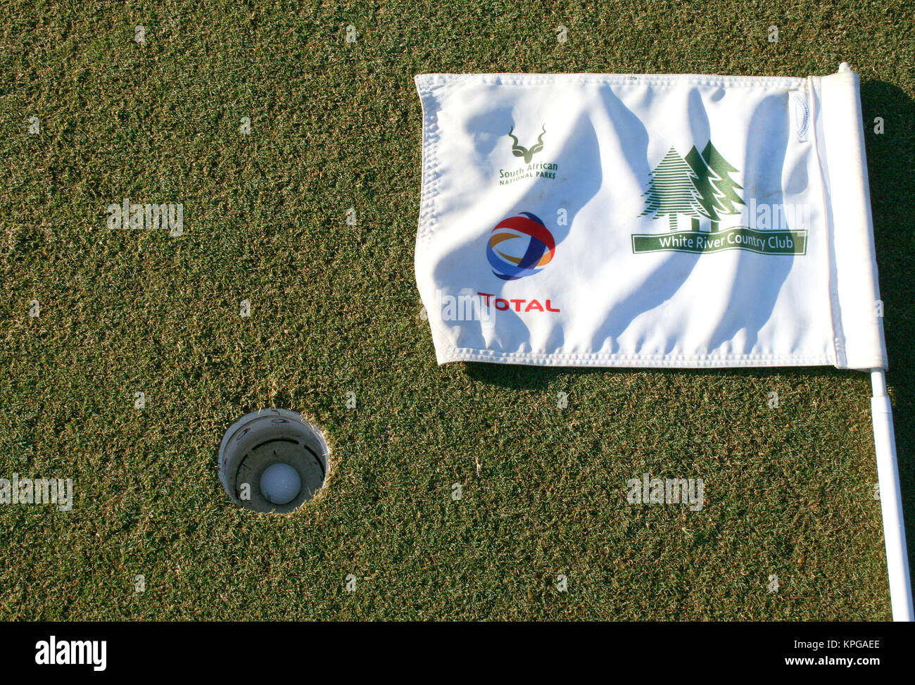 Golf ball in the hole and flag lying on the ground on putting green