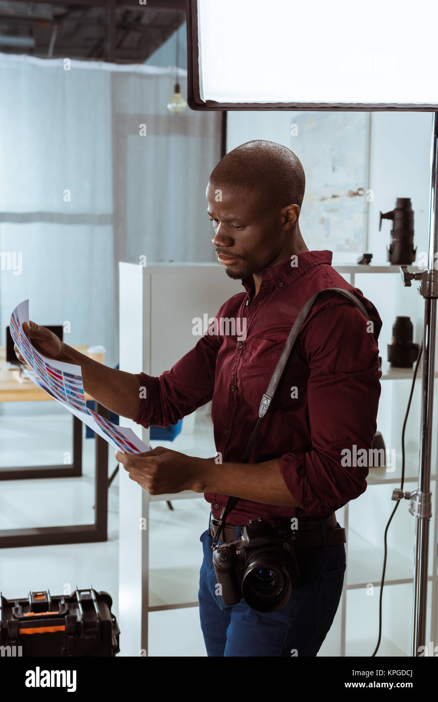 side view of african american photographer with photoshoot examples in