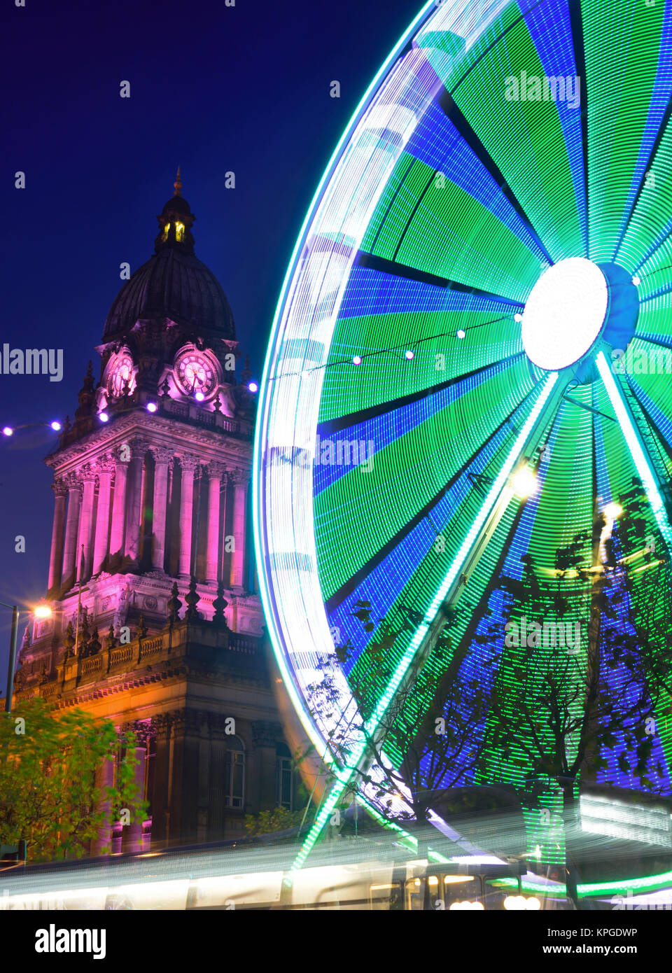 traffic passing funfair and christmas lights by leeds town hall at twilight yorkshire united kingdom Stock Photo