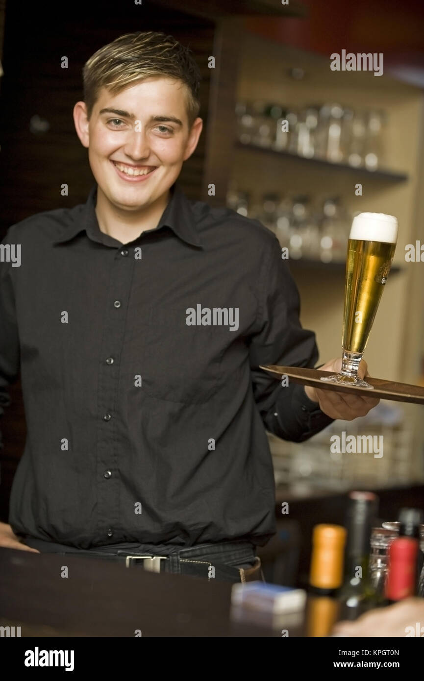 Model released , Junger, freundlicher Kellner mit Bierglas am Tablett - waiter served beer on a tablet Stock Photo