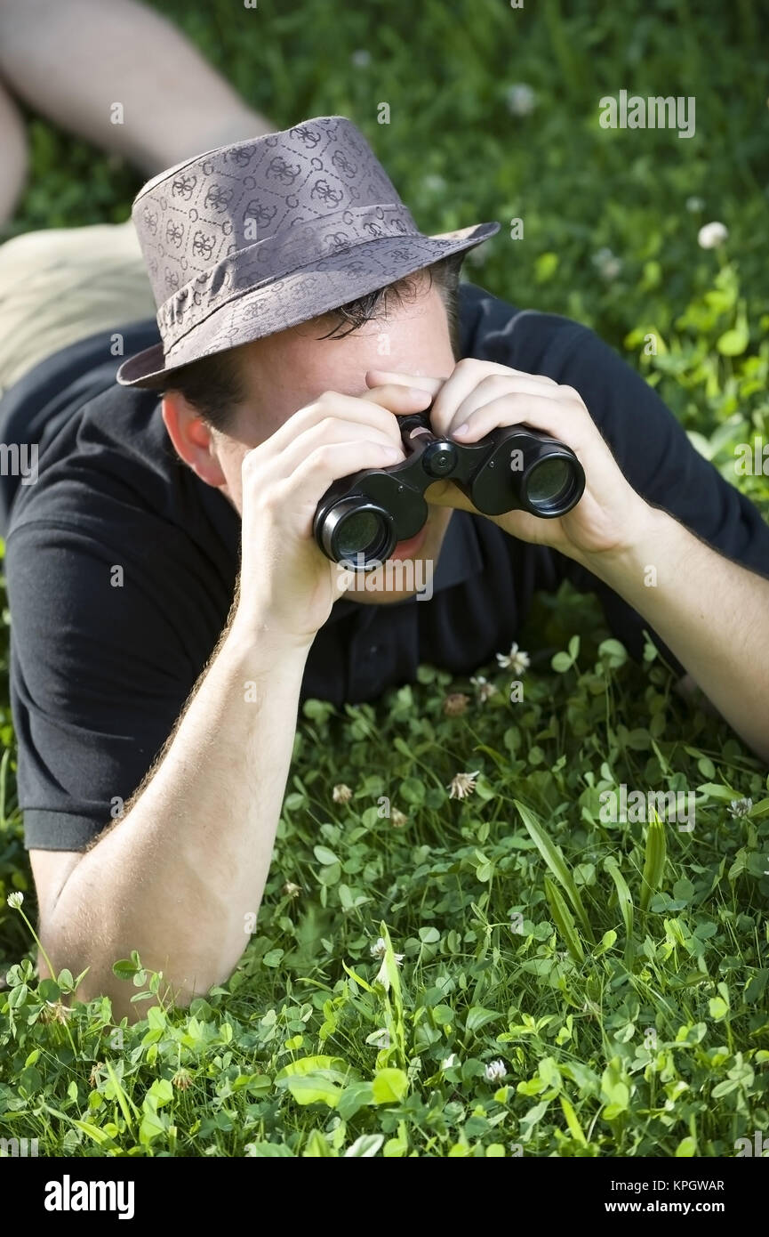 Model released , Junger Mann mit Fernglas in der Wiese - man with spy glass  in meadow Stock Photo - Alamy