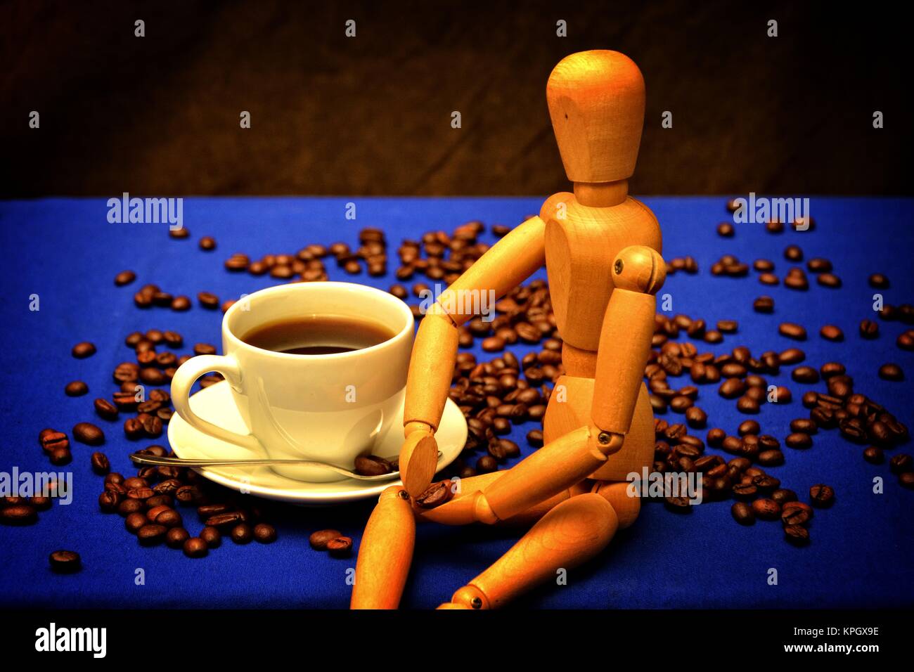 Coffee cup and coffee beans with wooden figure on wooden table Stock Photo